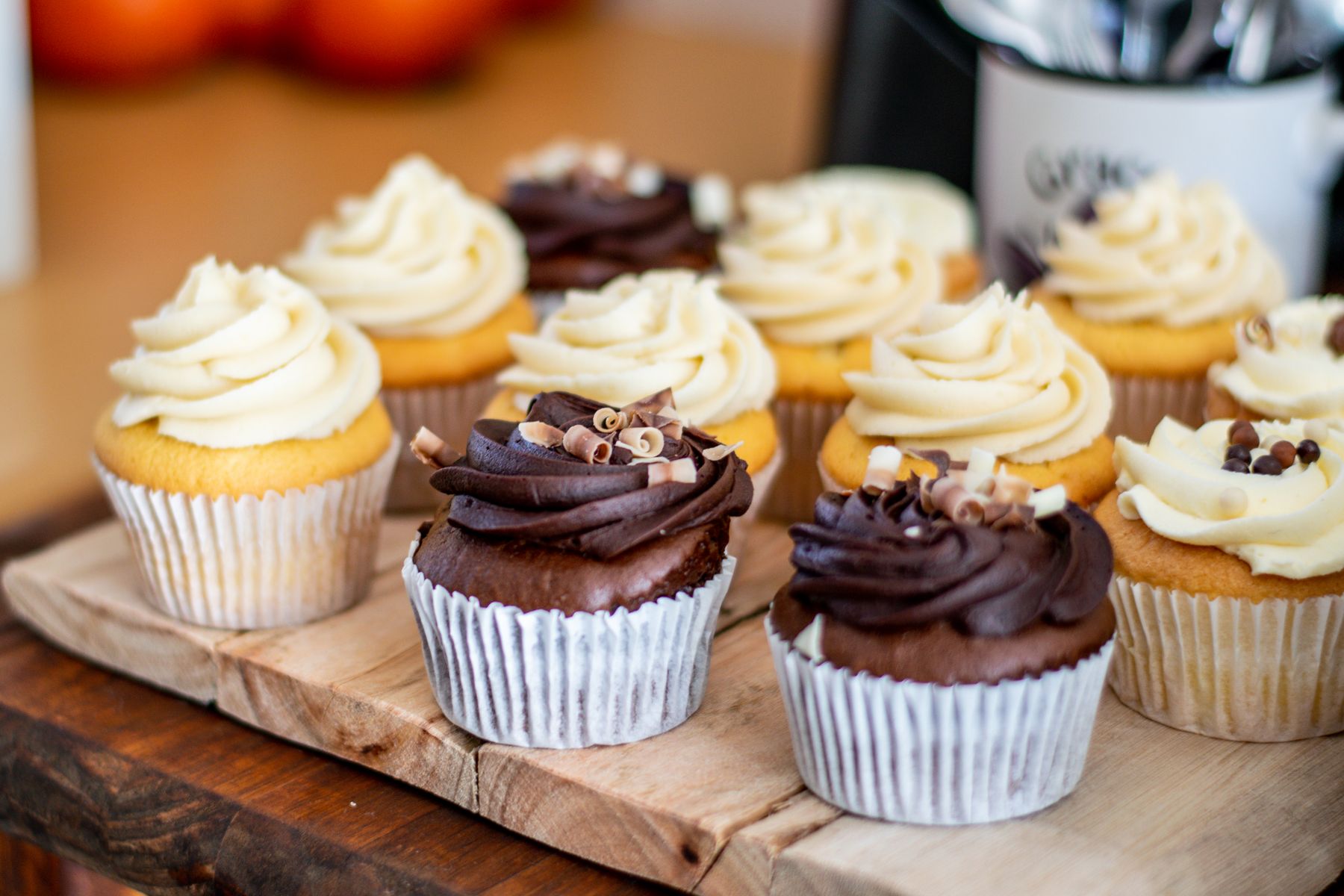 Vanilla and chocolate buttercream cupcakes arranged on a wooden board